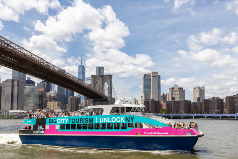 big-city-tourism-new-york-landmarks the Brooklyn bridge and Manhattan skyline including the one world trade center in the background of a freedom liberty cruise boat