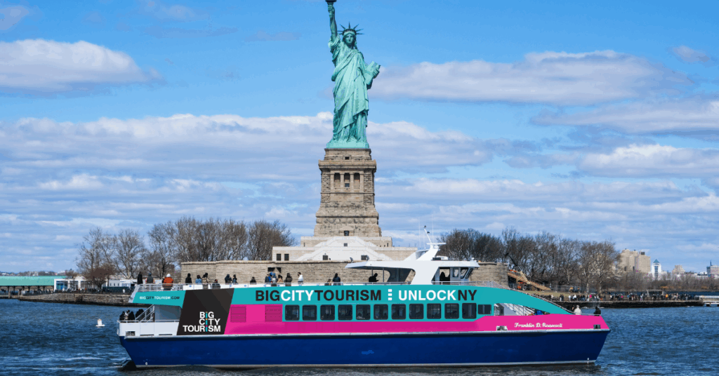 big city tourism boat in front of the statue of liberty on a nyc cruise