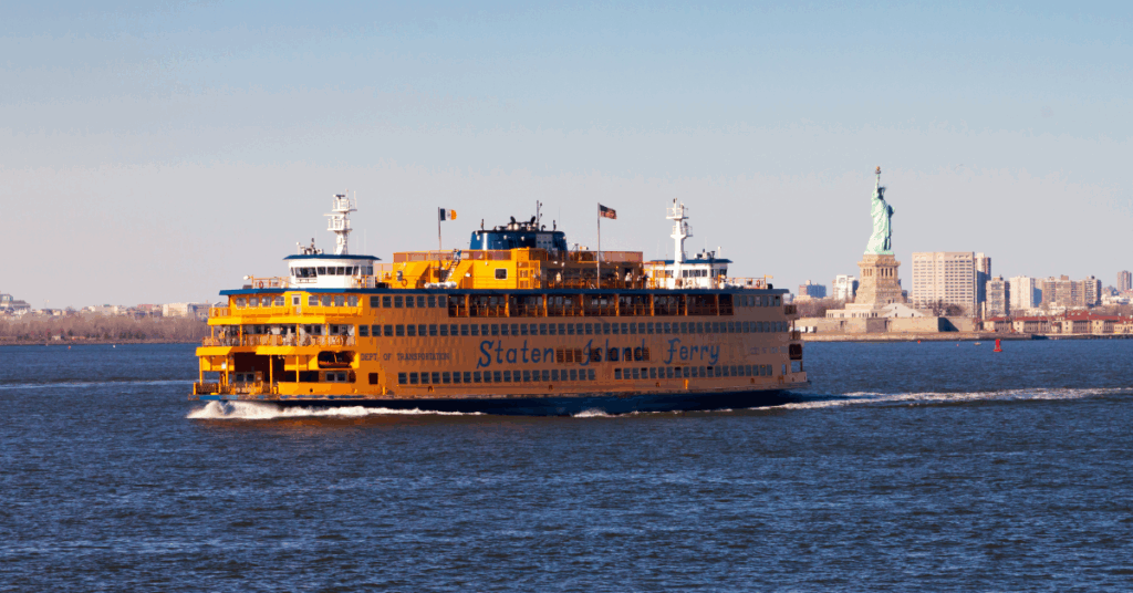 yellow staten island ferry with the statue of liberty in the background