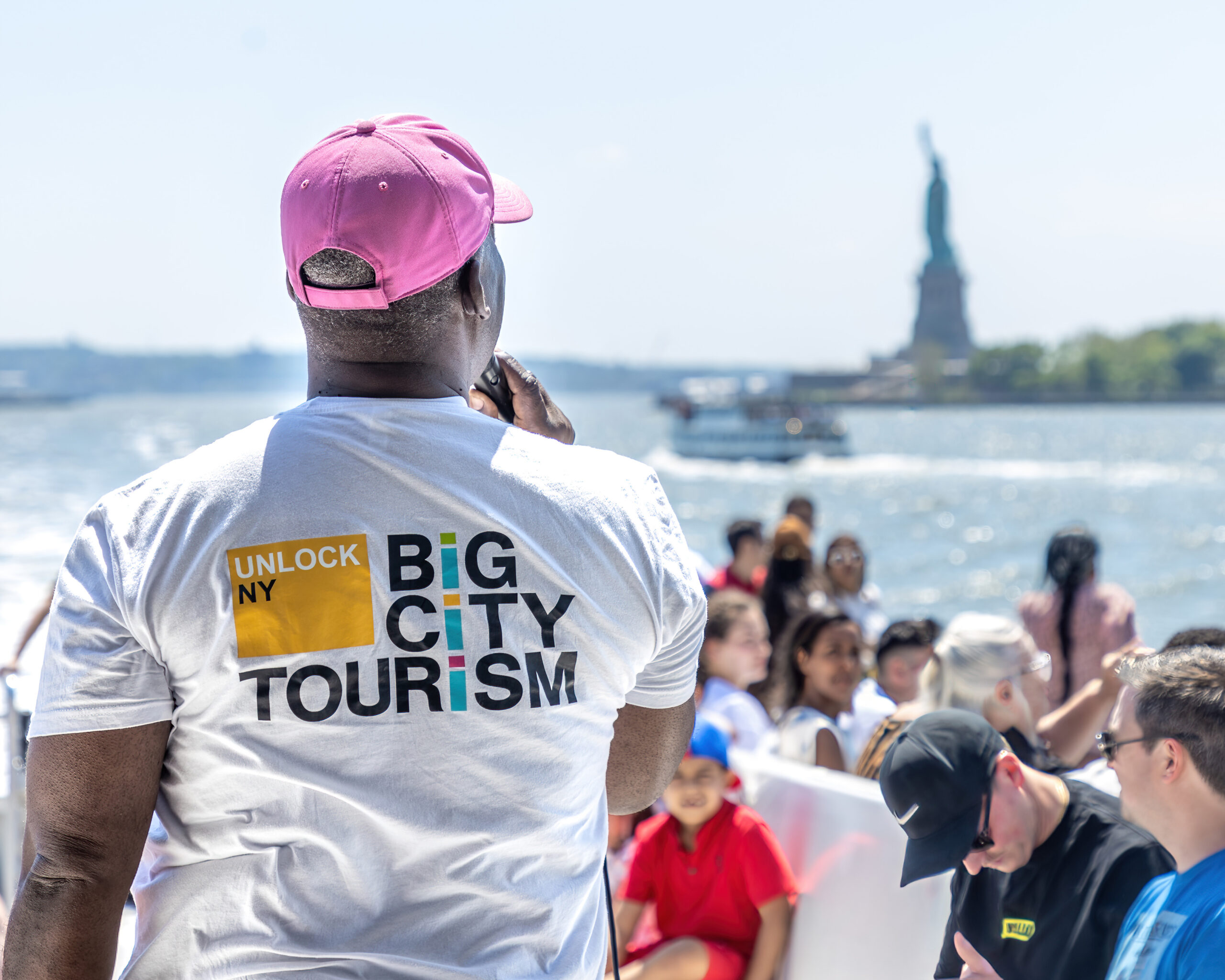 man with Big City Tourism shirt and pink hat on speaking to people