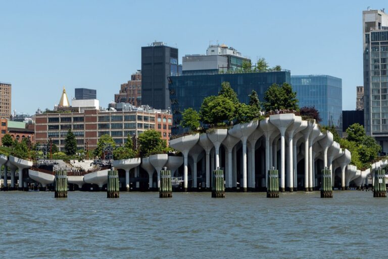 concrete pillars with trees on top and buildings in the background